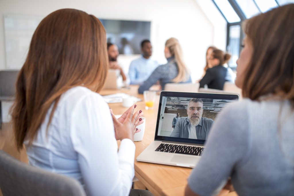 Business team having a meeting in an office. They are using laptop for video conference using Microsoft Teams.